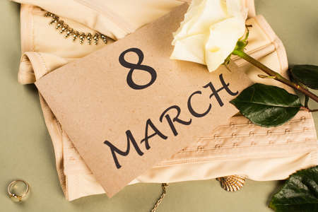 Top view of card with 8 march lettering on corset near rose on green backgroundの写真素材
