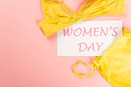 Top view of card with womens day lettering near bra on pink backgroundの写真素材