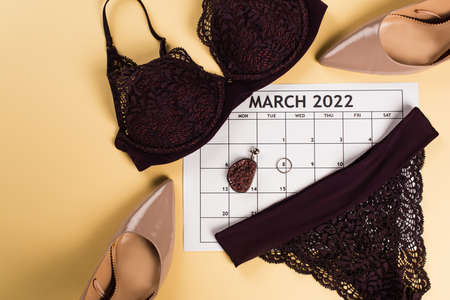 Top view of lingerie, heels and march calendar on beige backgroundの写真素材