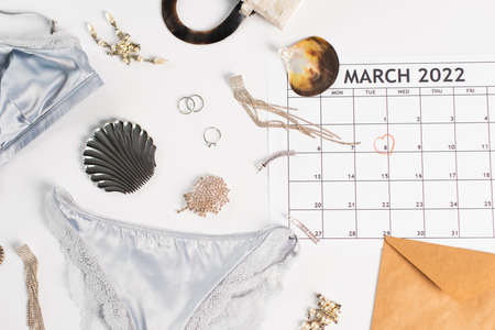 Top view of lingerie, accessories and march calendar on white backgroundの写真素材