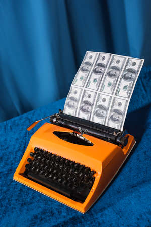 vintage typewriter and dollar banknotes on velour tablecloth and blue backgroundの写真素材