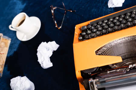 top view of retro typewriter, crumpled paper and blurred coffee cup on blue tableの写真素材