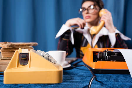 selective focus of vintage telephone near blurred newswoman talking on blue backgroundの写真素材