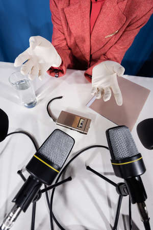 top view of microphones, dictaphone and glass of water near cropped woman in white glovesの写真素材