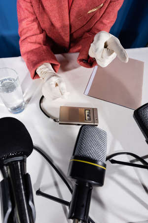top view of cropped woman in white gloves pointing with finger near microphone and dictaphoneの写真素材