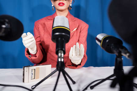 microphones near cropped vintage style woman giving interview on blue backgroundの写真素材