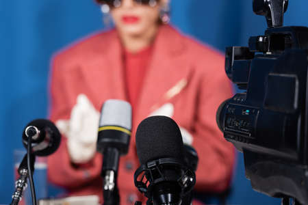 close up view of microphones and digital camera near cropped woman giving interview on blurred backgroundの写真素材