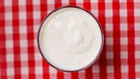 top view of bowl with fresh yogurt on checkered backgroundの写真素材