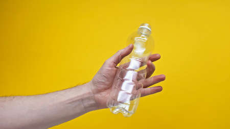 cropped view of man holding plastic bottle isolated on yellowの写真素材