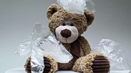 plastic bags falling on teddy bear isolated on greyの写真素材