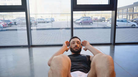 Bearded sportsman doing sit ups in gym