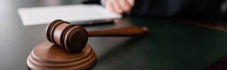 wooden gavel on desk near cropped judge on blurred background, banner