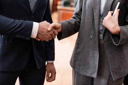 partial view of businessman and advocate shaking hands in courtの写真素材