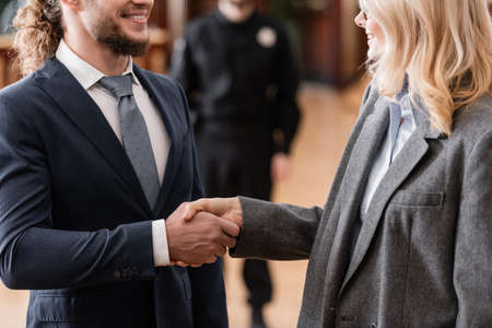 cropped view of smiling advocate shaking hands with happy businessman in courtの写真素材