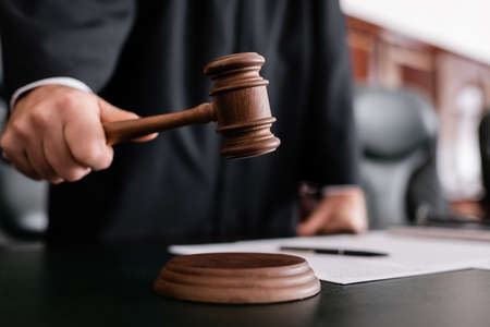 partial view of blurred judge holding gavel during sentencing in court
