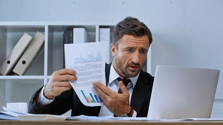 businessman showing infographics during video call on laptop