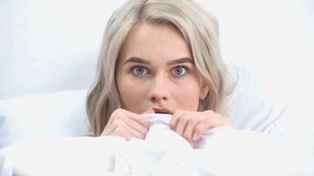 afraid woman covering with blanket in bed