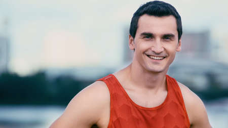 cheerful sportsman smiling at camera while standing outsideの写真素材