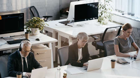 High angle view of business people using laptops near notebooks in office