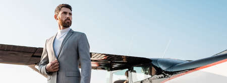 low angle view of successful businessman in suit standing near helicopter outdoors, banner