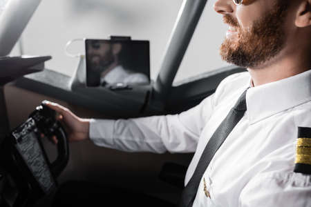 cropped view of cheerful pilot in uniform with badge using yokeの写真素材
