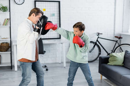 Preteen child boxing while training with dad at home