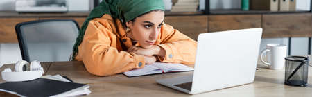 arabian woman focused on online webinar while learning at home, bannerの写真素材