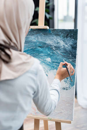 back view of blurred muslim woman drawing picture at homeの写真素材