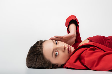 trendy young woman in red blazer lying on grayの写真素材