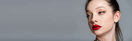 young stylish woman with red lips looking away isolated on grey, banner