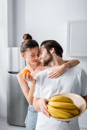 tattooed woman hugging man holding bowl with bananasの写真素材