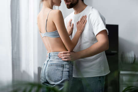 cropped view of woman in bra and bearded man hugging at homeの写真素材