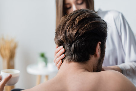 back view of shirtless man holding cup near blurred womanの写真素材