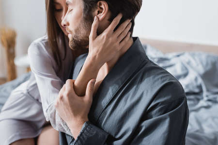 sensual woman in silk robe hugging bearded boyfriend with closed eyesの写真素材