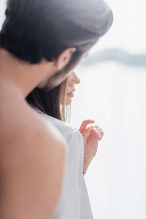 blurred and bearded man near young woman in silk robe