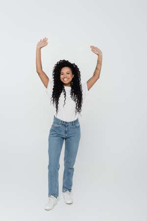 Cheerful tattooed african american woman waving hands on grey background