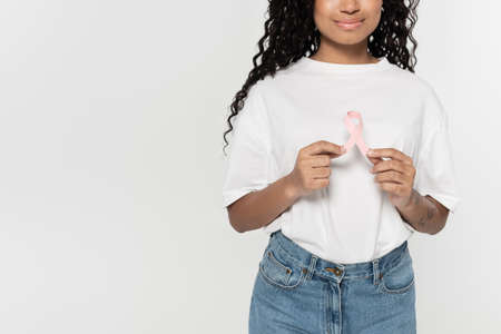 Cropped view of young african american woman holding pink ribbon of breast cancer awareness isolated...