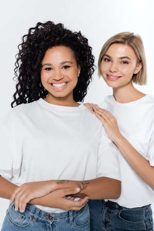 Happy woman hugging tattooed african american friend isolated on greyの写真素材