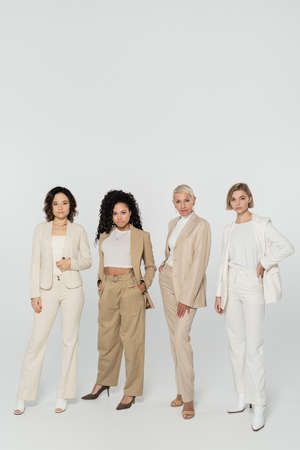 Multiethnic businesswomen posing and looking at camera on grey backgroundの写真素材