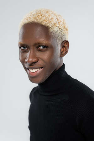 portrait of cheerful african american man with blue eyes isolated on greyの写真素材