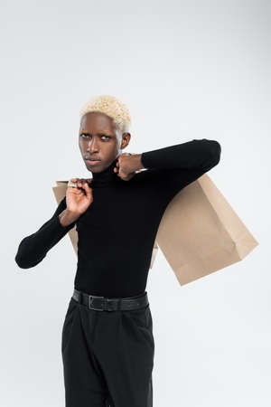 african american man holding shopping bags isolated on greyの写真素材