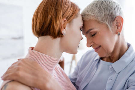happy woman smiling with closed eyes while standing face to face with lesbian girlfriend