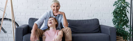 smiling lesbian woman looking at camera near laughing girlfriend, bannerの写真素材