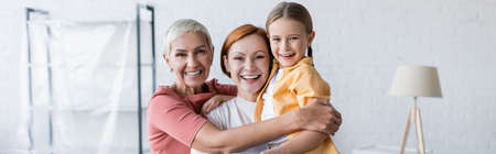 happy same sex couple with adopted daughter embracing in new apartment, banner