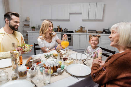 happy couple holding orange juice and fresh vegetable salad while having easter dinner at home