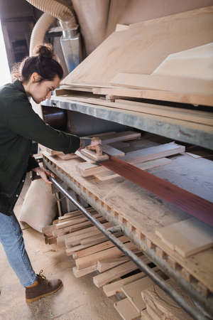 Side view of carpenter polishing planks in workshop
