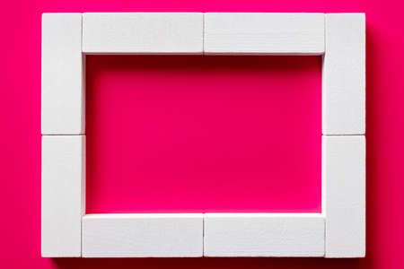 top view of white blocks frame on pink background