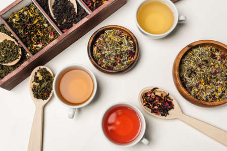 Top view of cups of tea near spoons and wooden bowls on white backgroundの写真素材