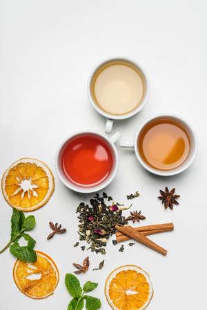 Top view of cups of tea near spices and mint on white backgroundの写真素材