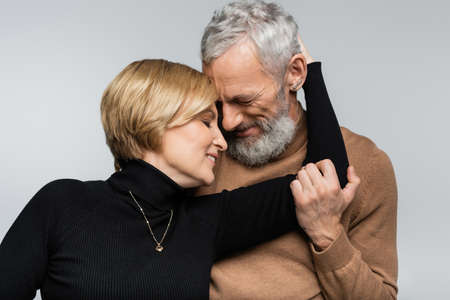 Portrait of mature woman hugging gray haired husband isolated on grayの写真素材